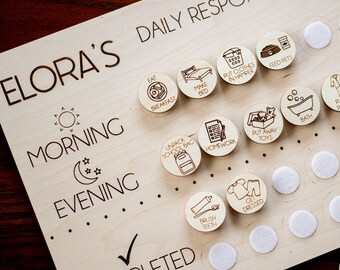 May include: A wooden board with the text "ELORA'S DAILY RESPONSIBILITIES" and a checklist of daily tasks for a child. The board has a section for morning and evening tasks. The tasks include "Eat Breakfast", "Make Bed", "Put Clothes in Hamper", "Feed Pets", "Unpack School Bag", "Homework", "Put Away Toys", "Bath", "Put on Pajamas", "Quiet Time", "Brush Teeth", "Get Dressed", and "Completed".