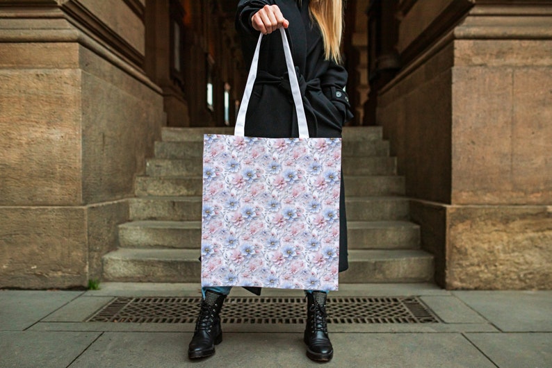 May include: A white tote bag with a floral pattern featuring pink and blue flowers. The bag has white straps.