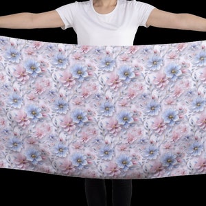 May include: A white fabric scarf with a repeating pattern of pink and blue flowers. The flowers are stylized and have a 3D effect.