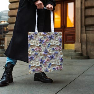 May include: A white tote bag with a floral pattern featuring purple butterflies and pink flowers. The bag has white handles.