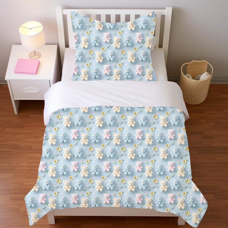 May include: A light blue bed set featuring a repeating pattern of teddy bears in pastel colors. The set includes a pillowcase and a duvet cover, with small yellow flower accents. The bed is made up with a white sheet.