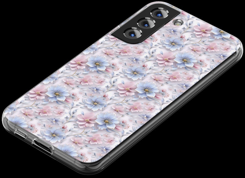 May include: A clear phone case with a floral design featuring pink and blue flowers on a white background. The case has a raised camera bump with three black camera lenses.