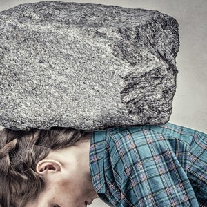 May include: A woman is lying on a stack of books with a large rock on top of her head. The text "STRESS BUSTER" is written above the rock. The image is a metaphor for the feeling of being overwhelmed by stress.