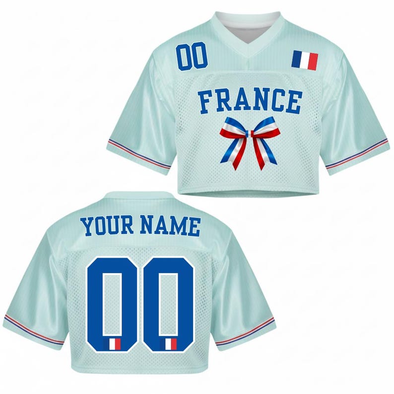 May include: Light blue cropped jersey with the word "FRANCE" in blue block letters, a blue, white, and red bow, and the French flag. The jersey has the number "00" on the front and back, and the words "YOUR NAME" on the back.