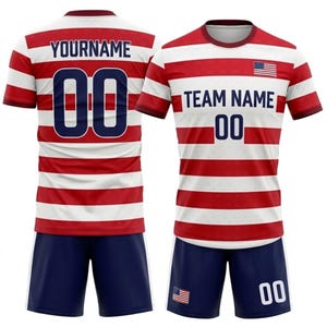 May include: A red and white striped soccer uniform with the text "YOURNAME" and the number "00" on the back of the jersey. The front of the jersey has the text "TEAM NAME" and the number "00". The shorts are navy blue.