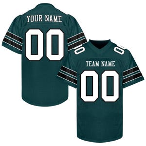 Puede incluir: Dos camisetas de f&uacute;tbol verdes con n&uacute;meros y letras blancas. Una camiseta muestra "YOUR NAME" y el n&uacute;mero "00" en la espalda. La otra muestra "TEAM NAME" y "00". Ambas tienen rayas blancas y negras en las mangas.