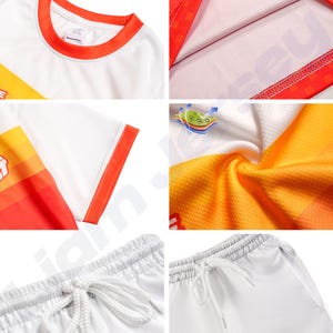 Op de afbeelding: Close-up shots van een wit atletisch shirt met oranje en gele accenten, en witte atletische shorts. Het shirt heeft oranje afwerking op de kraag en mouwen. De shorts hebben een tailleband met trekkoord. De stof lijkt een ademend, atletisch materiaal te zijn.