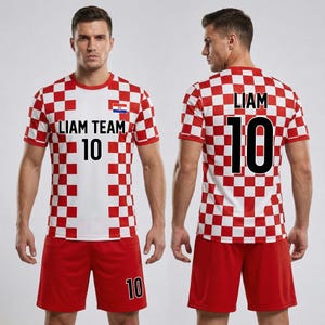 以下が含まれることがあります： 赤と白のチェック柄のサッカーユニフォームとショーツのセット。ジャージには前面に「LIAM TEAM 10」、背面に「LIAM 10」と書かれています。ショーツには右脚に数字の「10」が入っています。ジャージにはクロアチアの国旗が描かれています。