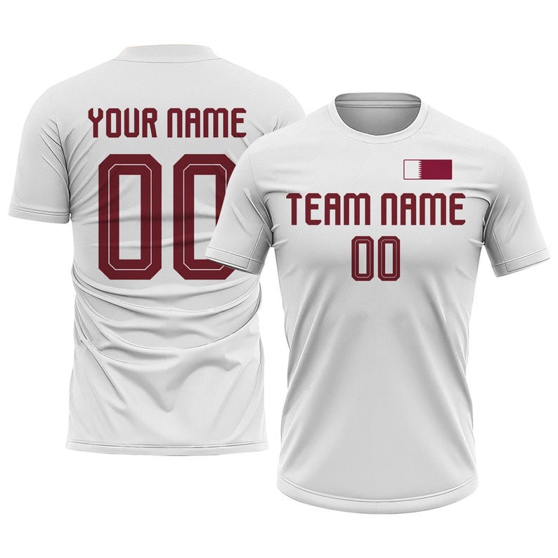 Op de afbeelding: Twee witte sportshirts met bordeauxrode tekst en cijfers. E&eacute;n shirt toont "YOUR NAME" en het nummer "00" op de achterkant. Het andere shirt heeft "TEAM NAME" en het nummer "00" op de voorkant, met een bordeauxrode en witte vlag.