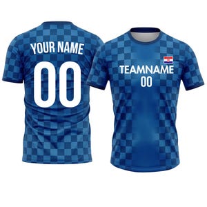以下が含まれることがあります： チェック柄の青いサッカーユニフォーム2枚。1枚は背中に「YOUR NAME」と数字「00」が表示されています。もう1枚は「TEAMNAME」、数字「00」、クロアチアの国旗が表示されています。