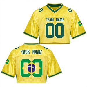 Puede incluir: Una camiseta de f&uacute;tbol amarilla recortada con detalles verdes y la bandera brasile&ntilde;a en la manga. La parte delantera muestra "TEAM NAME" encima del n&uacute;mero "00". La parte trasera tiene "YOUR NAME" y el n&uacute;mero "00" con la bandera brasile&ntilde;a dentro.