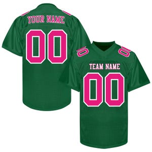 Puede incluir: Dos camisetas de f&uacute;tbol verdes con detalles rosas. Una camiseta muestra "YOUR NAME" y el n&uacute;mero "00". La otra muestra "TEAM NAME" y el n&uacute;mero "00". Ambas camisetas tienen n&uacute;meros rosas con contornos blancos.