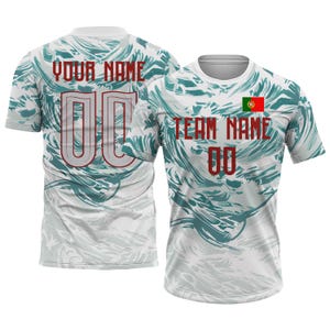 Op de afbeelding: Wit en teal gekleurd sportshirt met patroon. De achterkant toont "YOUR NAME" en "00". De voorkant heeft "TEAM NAME", het nummer "00" en een Portugese vlag. Korte mouwen.
