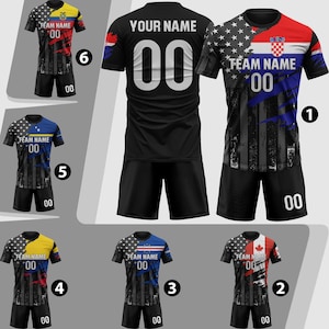 Puede incluir: Una colecci&oacute;n de camisetas de f&uacute;tbol con varios dise&ntilde;os y colores. Cada camiseta presenta un nombre de equipo y el n&uacute;mero "00". Las camisetas muestran banderas y patrones, incluyendo estrellas, rayas y bloques de color. Las camisetas son negras, rojas, azules, amarillas y blancas.