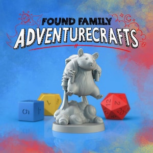 May include: A gray 3D-printed figurine of a hamster wearing a jetpack and holding a drink. The text "FOUND FAMILY ADVENTURECRAFTS" is above the hamster. Dice in blue, yellow, and red are in the background.