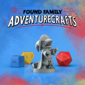 May include: A gray figurine of a frog-like character wearing a hat and robe, with the text "FOUND FAMILY ADVENTURECRAFTS" above. A blue six-sided die, a yellow eight-sided die, and a red twenty-sided die are in the background.