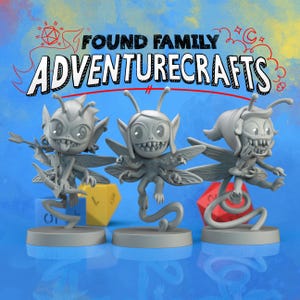May include: Three gray fantasy figurines with insect-like wings and mischievous expressions. The figurines are on round bases, with the text "FOUND FAMILY ADVENTURECRAFTS" above them. Dice in yellow and red are in the background.