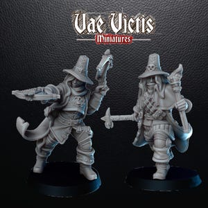 Puede incluir: Dos figuras en miniatura grises de personajes de fantasía. Una figura sostiene una ballesta, la otra un martillo y una antorcha. Ambos llevan sombreros y abrigos largos. El texto "Vae Victis Miniatures" está en la parte superior.