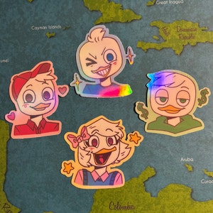May include: Four holographic stickers featuring cartoon ducks with different expressions. The ducks are wearing different outfits, including a red shirt, a blue shirt, a green shirt, and a pink shirt. The stickers are on a map background.
