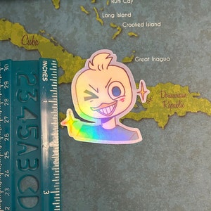 May include: A holographic sticker of a cartoon duck with a mischievous grin, winking, and holding up a finger. The duck is yellow with a blue eye and a red blush on its cheek. The sticker has a rainbow iridescent finish.