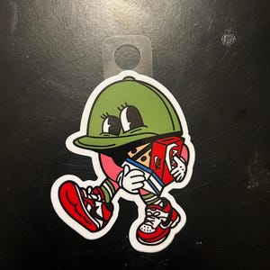 May include: A cartoon character wearing a green hat and red shoes is walking while carrying a red box with the word "NIKE" on it.