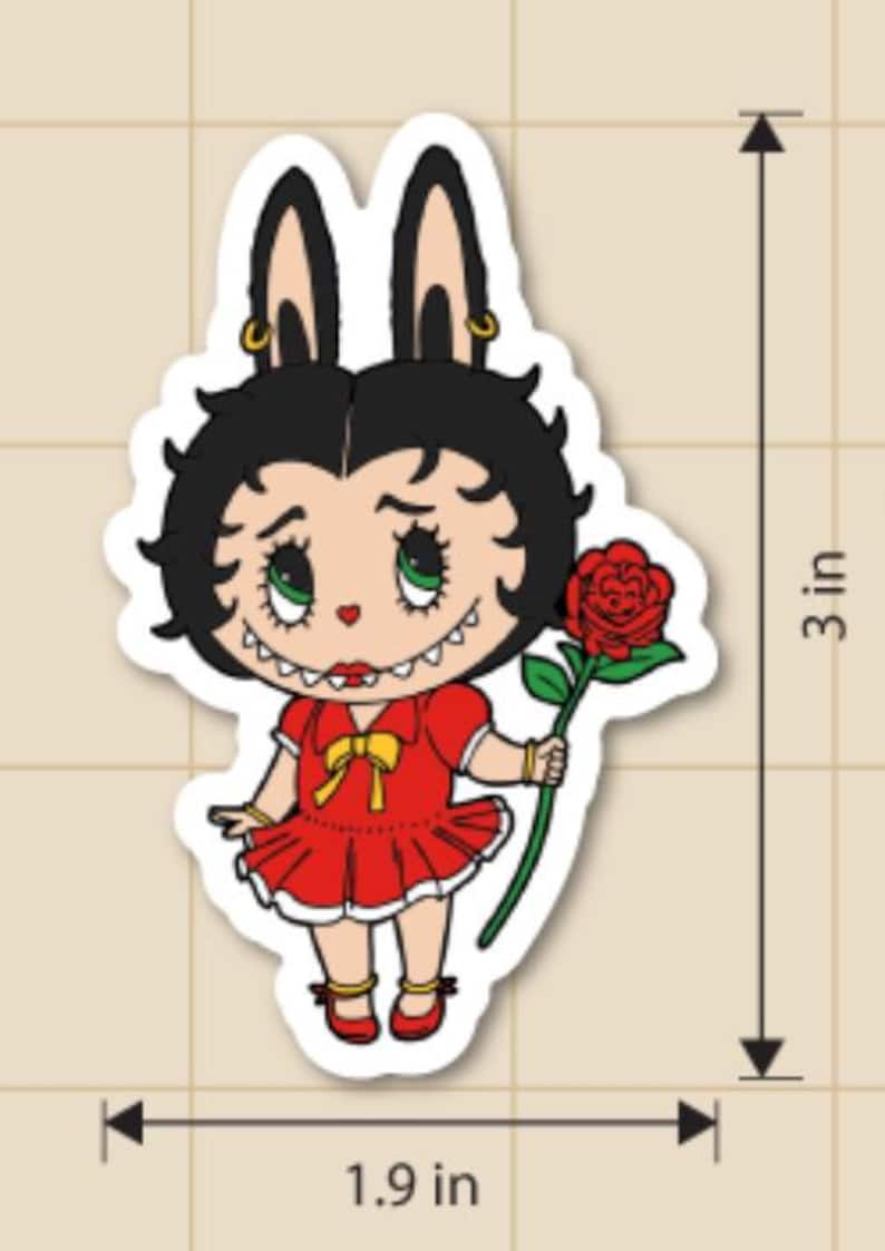 May include: A die-cut sticker featuring a cartoon character with black hair and bunny ears, wearing a red dress and holding a red rose. The sticker is 3 inches tall and 1.9 inches wide.