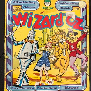 Könnte beinhalten: Ein gelbes Schallplattencover mit einem Bild von Dorothy, dem Blechmann, dem Feigen Löwen und dem Vogelscheuche aus dem Zauberer von Oz. Das Cover ist mit "Der Zauberer von Oz" betitelt und zeigt das Logo von Peter Pan Records.