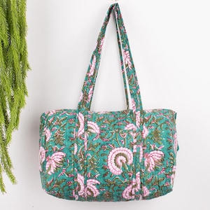 Peut inclure: Un sac fourre-tout en coton bleu sarcelle avec un imprimé floral composé de fleurs roses et vertes. Le sac a deux longues anses et une fermeture éclair.