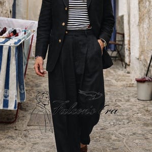 Può includere: Un blazer nero con bottoni dorati, abbinato a pantaloni neri a pieghe. L'outfit include una maglia a righe, una sciarpa fantasia e un fazzoletto da taschino giallo. L'immagine presenta il testo "Falcon's Era".