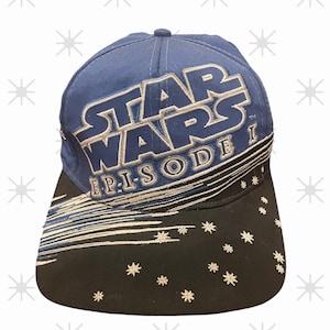 Könnte beinhalten: Blaue Baseballkappe mit dem Star Wars-Logo in Silber und Weiß und dem Text "EPISODE I". Der schwarze Schirm hat weiße Stern- und Liniendesigns. Eine klassische Mütze für Fans der Star Wars-Reihe.