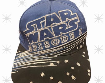Peut inclure: Casquette de baseball bleue avec le logo Star Wars argenté et blanc, et le texte "EPISODE I". La visière noire présente des motifs d'étoiles et de lignes blanches. Un chapeau classique pour les fans de Star Wars.