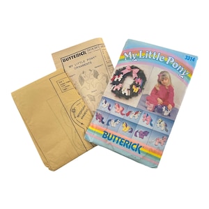 Könnte beinhalten: Ein Vintage-Butterick-Schnittmuster für "My Little Pony"-Ornamente. Das Muster enthält ein Cover mit einem Foto eines Mädchens und Ponys sowie Schnittmusterteile und Anweisungen. Das Cover ist blau, rosa und gelb.