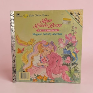 May include: A Big Little Golden Book titled Lady Lovely Locks and the Pixietails: Silkypup's Butterfly Adventure. The cover features a character with long pastel hair, a pink creature, and small animals amidst flowers, with a silver foil spine.