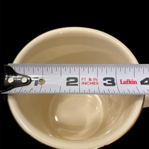 May include: A white ceramic mug with a gold rim, measured with a tape measure to be 3 inches in diameter.