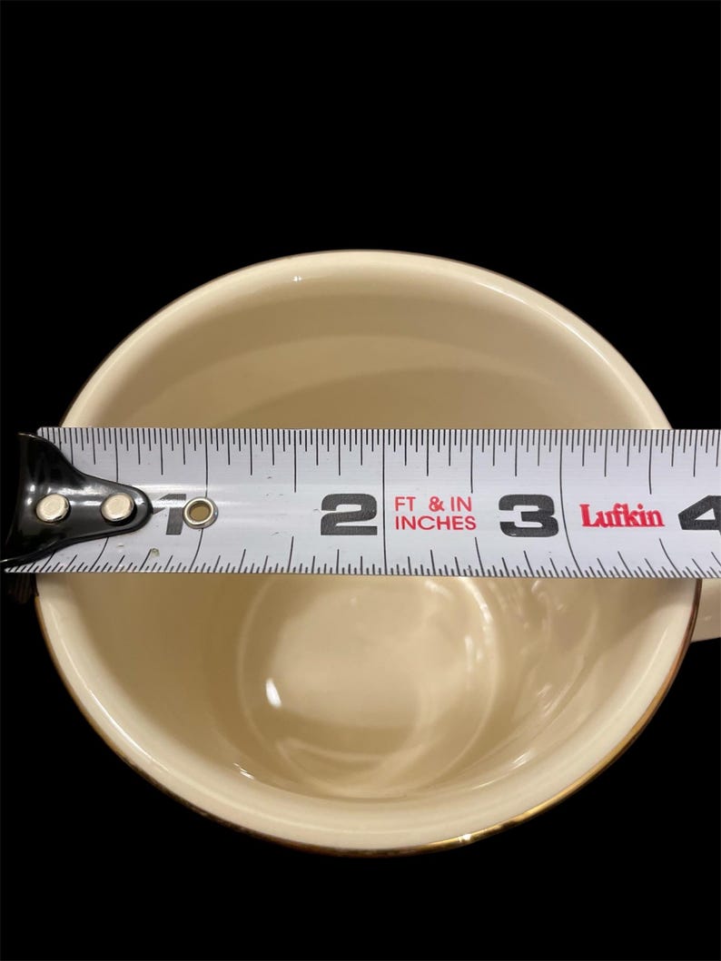 May include: A white ceramic mug with a gold rim, measured with a tape measure to be 3 inches in diameter.