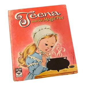 Peut inclure: Un livre pour enfants vintage intitulé Teena and the Magic Pot avec une couverture rouge. L'illustration montre un personnage blond portant un bonnet blanc et une robe bleue, regardant une marmite noire avec de la vapeur. Logo Top Top Tales.
