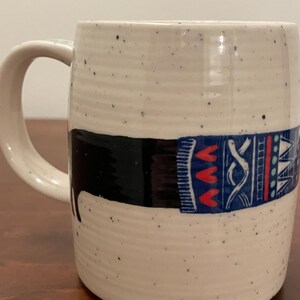 May include: A set of three ceramic mugs with a speckled, matte finish. The mugs are in shades of cream, light gray, and dark gray. Each mug has a simple, minimalist design and a rounded handle. Perfect for coffee or tea.
