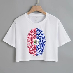 May include: White cropped t-shirt with a fingerprint design featuring the flag of Haiti in red, blue, and white.