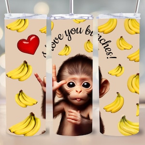 Könnte beinhalten: Drei 20 Unzen Edelstahlbecher mit hellbraunem Hintergrund und einem Muster aus gelben Bananen. Der mittlere Becher zeigt einen niedlichen Affen mit großen braunen Augen und dem Text "Ich liebe dich sehr!" Die Becher sind perfekt für heiße oder kalte Getränke.