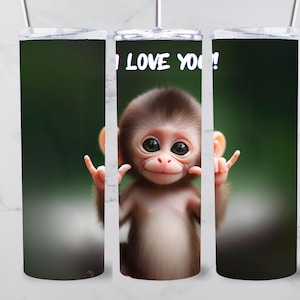 Könnte beinhalten: Ein Edelstahlbecher mit einem niedlichen Affenbild und dem Text "I LOVE YOU!" darauf gedruckt. Der Affe ist braun und hat große Augen. Der Hintergrund ist verschwommen grün.