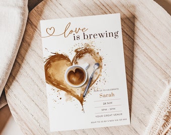 May include: A white card with brown coffee-themed artwork and the text "love is brewing" in gold lettering. The card is an invitation to celebrate Sarah on November 28th at 3pm. The invitation includes the text "RSVP to [phone number] by November 12th."