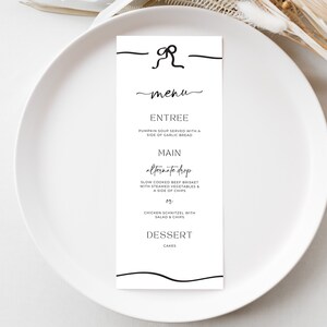 May include: A black and white menu card with a handwritten font. The menu includes the following options: Entree, Main, and Dessert. The main course options are "alternate drop" and "Chicken Schnitzel with Salad & Chips".