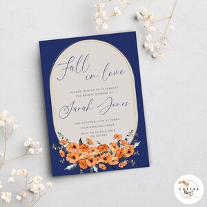 K&ouml;nnte beinhalten: Eine marineblaue Einladung zur Brautparty mit einem goldenen ovalen Rahmen und dem Text "Fall in love". Die Einladung zeigt eine Aquarell-Illustration von orangefarbenen Blumen und Gr&uuml;n.