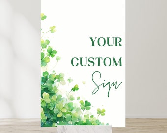 Könnte beinhalten: Ein weißes Schild mit grünen Kleeblättern auf der linken Seite und dem Text "YOUR CUSTOM Sign" in grüner Schrift auf der rechten Seite.