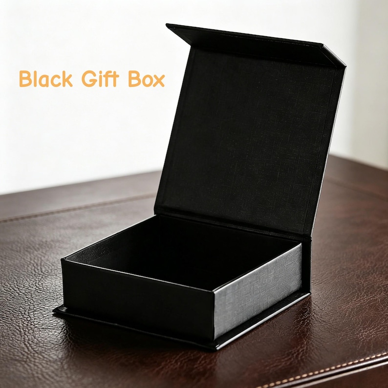 May include: A black gift box with an open lid. The box is rectangular and sits on a brown surface. The text "Black Gift Box" is in the upper left corner.