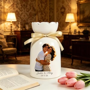 Puede incluir: Un jarr&oacute;n de cer&aacute;mica blanco con borde festoneado y cinta crema. El jarr&oacute;n muestra una foto de una pareja, con los nombres "Justin & Amy" y la fecha "18-5-26" impresos debajo. Tulipanes rosas en primer plano.