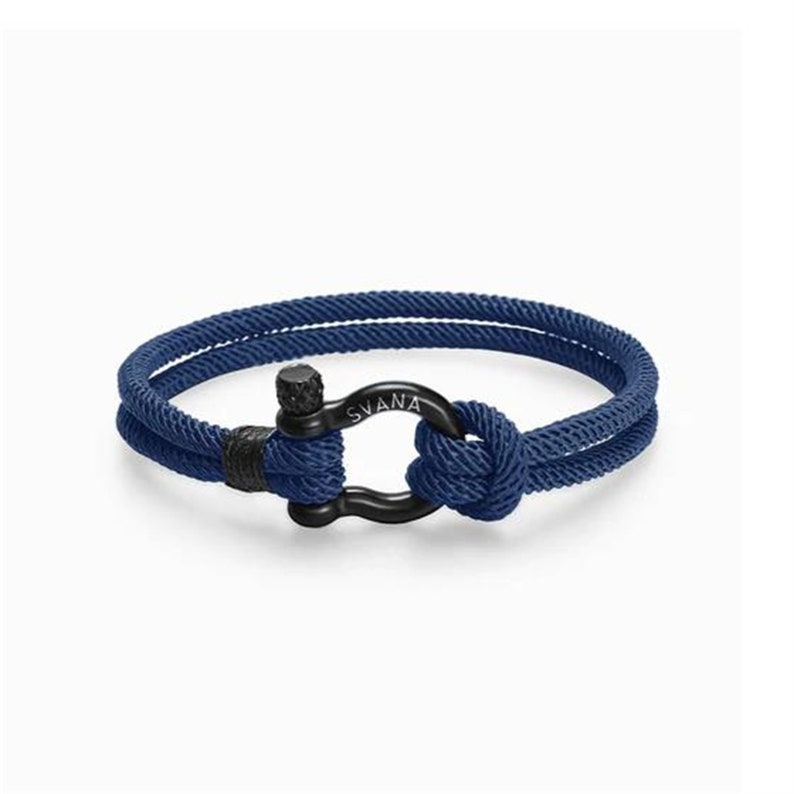 May include: A blue rope bracelet with a black metal clasp. The clasp has the word "SVANA" engraved on it.