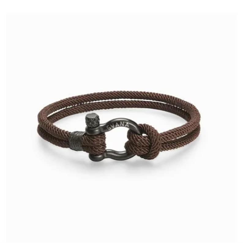 May include: A brown rope bracelet with a black metal clasp. The clasp has the word "SVANA" engraved on it.