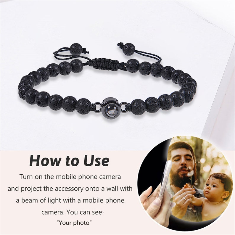 May include: A black lava rock beaded bracelet with a small round charm that projects an image when held up to a phone camera. The charm has a silver ring around it. "How to Use" is written in white text on a pink background with instructions on how to use the bracelet.