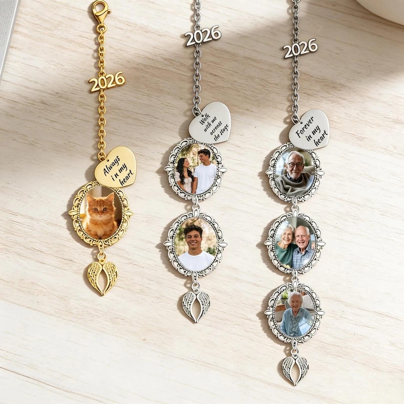 Pode incluir: Tr&ecirc;s amuletos de carro com fotos personalizadas. Um amuleto dourado apresenta uma foto de gato e o texto "Always in my heart". Dois amuletos prateados exibem fotos de pessoas e o texto "Walk with me across the stage" e "Forever in my heart". Cada amuleto inclui o ano "2026".